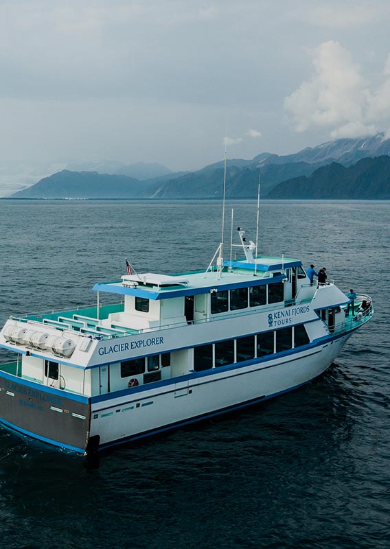 A boat cruises on the ocean near forest covered hillside coasts