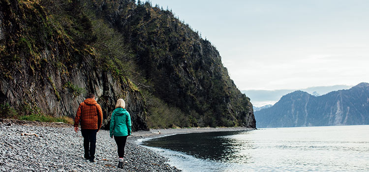 A couple wearing rain coats walks along the river in