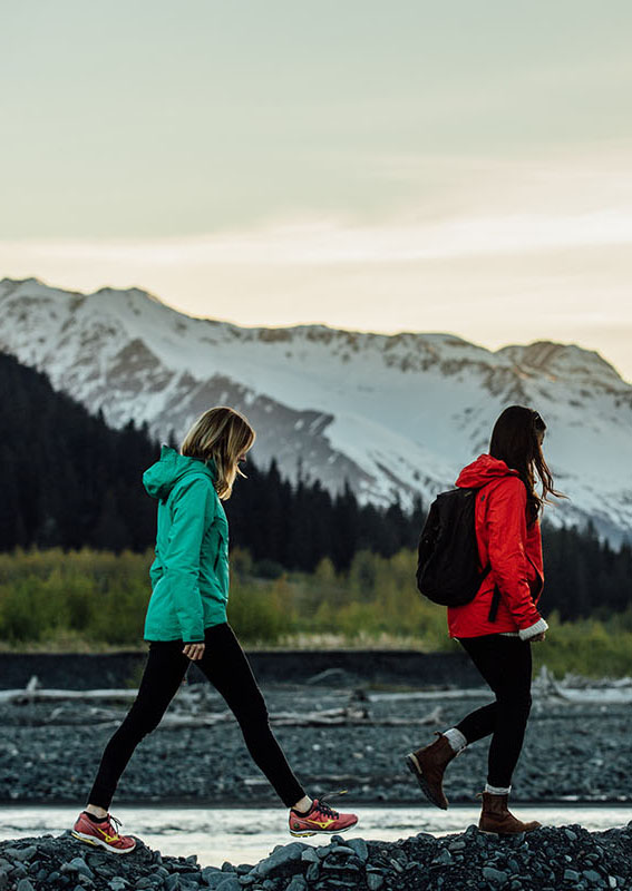 Two people walk along a riverside