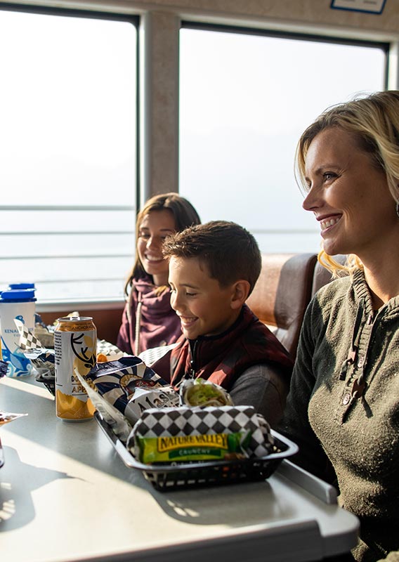 A family sitting together at a windowside table on a boat.