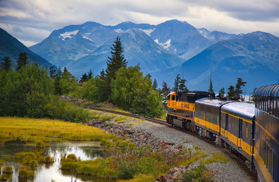 Train traveling through valley with mountain view