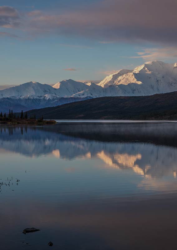 A view across a lake towards a tall mountain covered in snow.