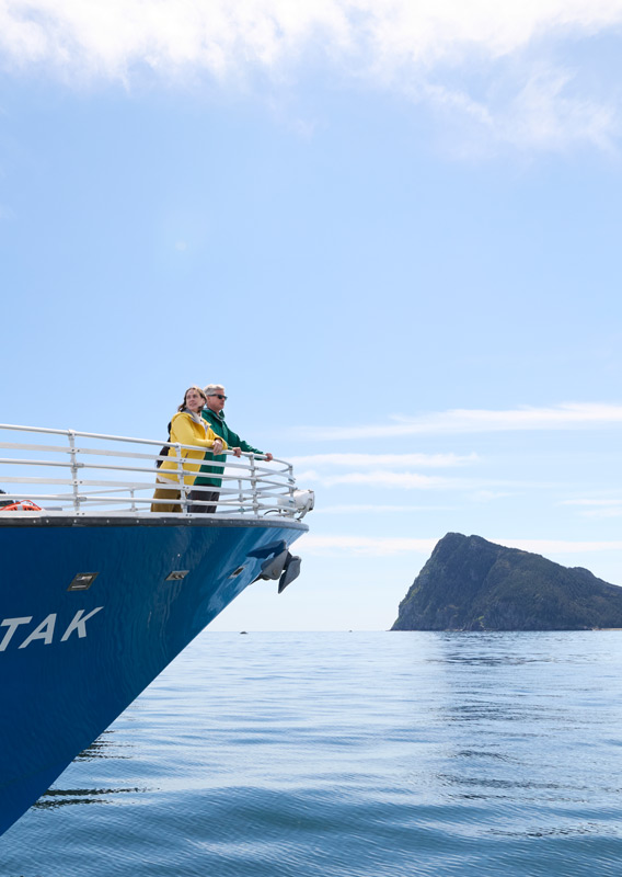 A couple standing on the bow of a KFT boat, looking at the view.
