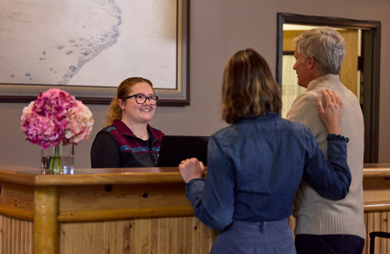 Guests talking with reservation staff at Seward Windsong Lodge check-in desk