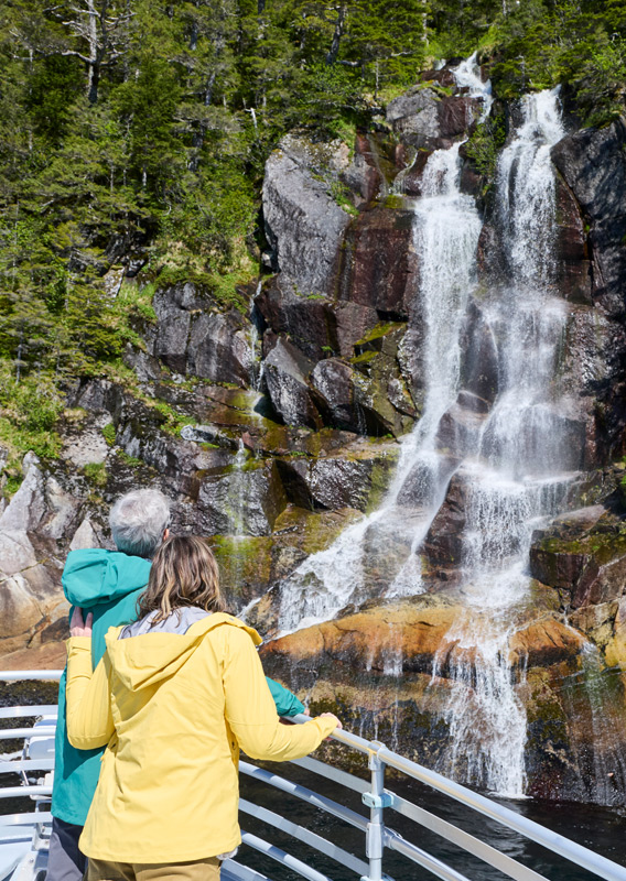 A couple viewing a waterfall from a Kenai Fjords Tour boat